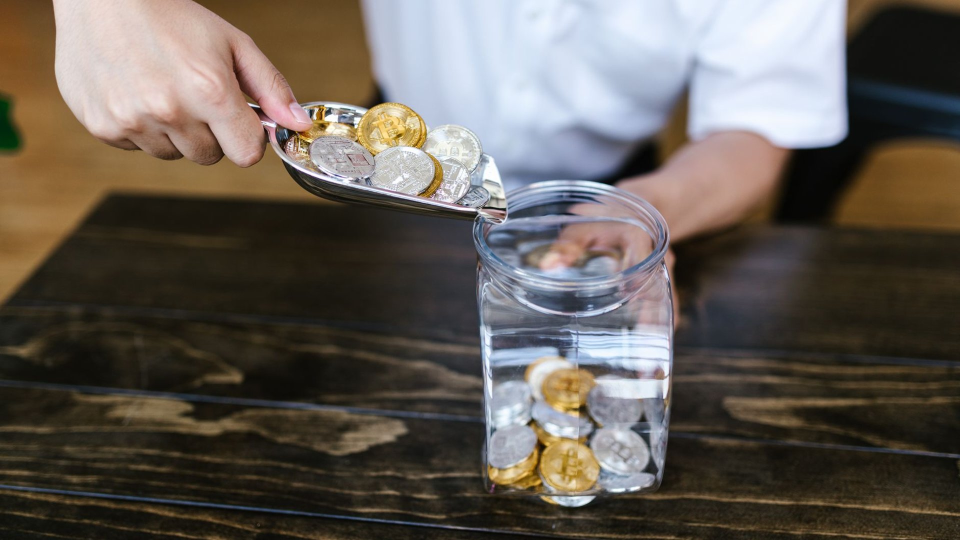Hand schüttet Krypto-Münzen in ein Glas, Symbolbild Stablecoin-Nutzung im Casino